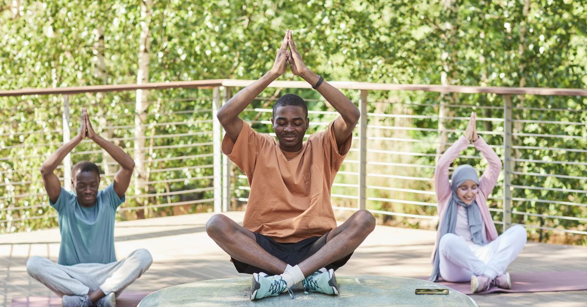 A diverse group of people meditating outdoors in a serene setting, promoting wellness and relaxation.